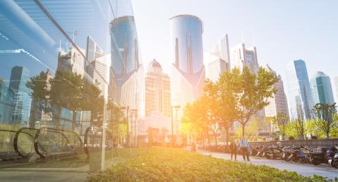 Panoramic view of a skyscraper with a green walkway in front of it 