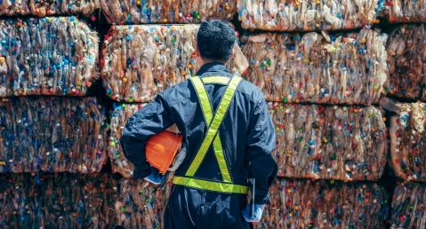 Engineer stands and looks at towers of plastic bales