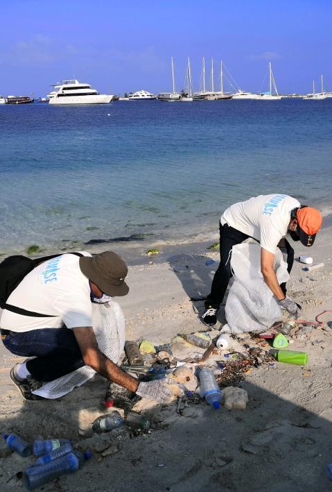 Zwei Frauen reinigen den Strand von Plastik. 