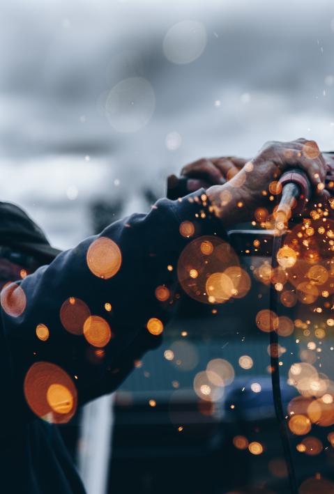 Workers' hands with welding equipment and sparks