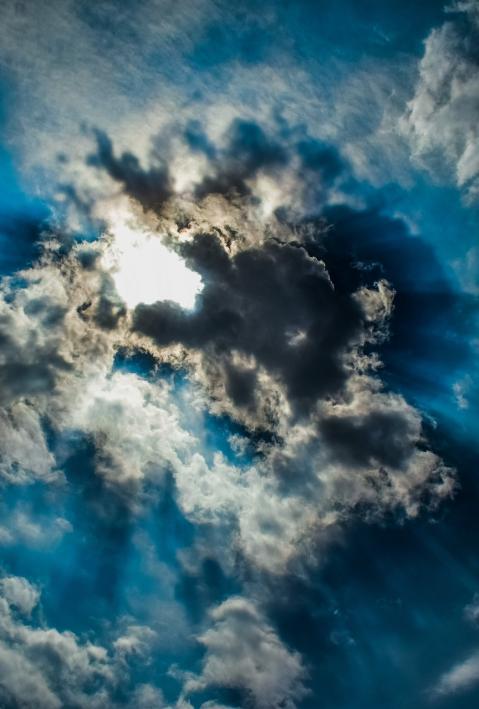 Durch dunkle Wolken scheinen Sonnenstrahlen. 