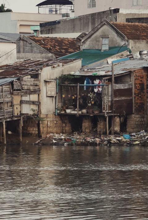 Blechh&uuml;tten stehen auf Holzs&auml;ulen &uuml;ber einem schmutzigen Gew&auml;sser.