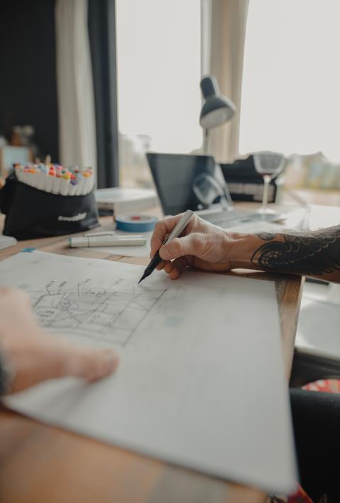Hand mit Stift in der Hand arbeitet an einem Dokument.