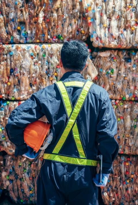 Engineer stands and looks at towers of plastic bales
