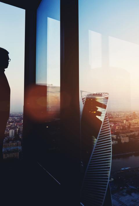 Silhouette of a person in the office looks far over the city