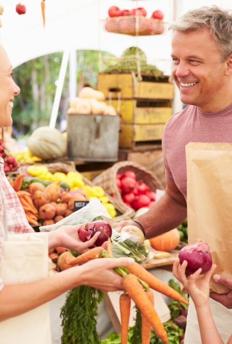 Family Buying Fresh Vegetables At Farmers Market Stall