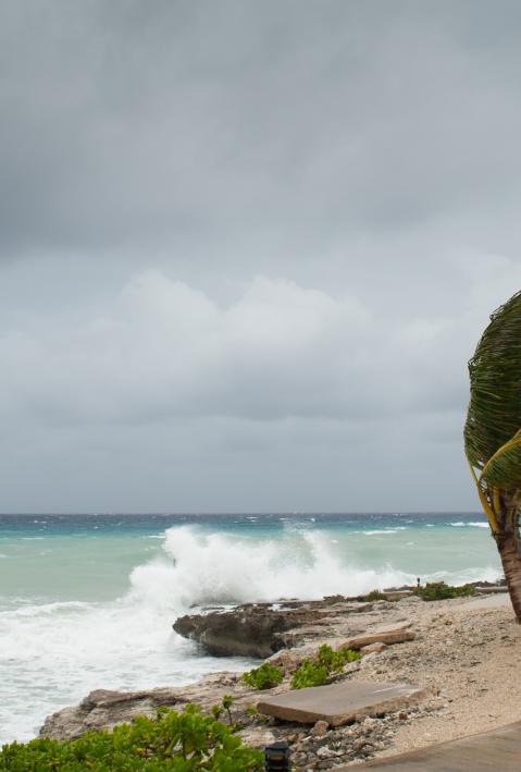 A hurricane is about to batter this caribbean beach hut. The seas are raging and the skies show the tropical storm as the power of nature is demonstrated. Waves crash on the shore