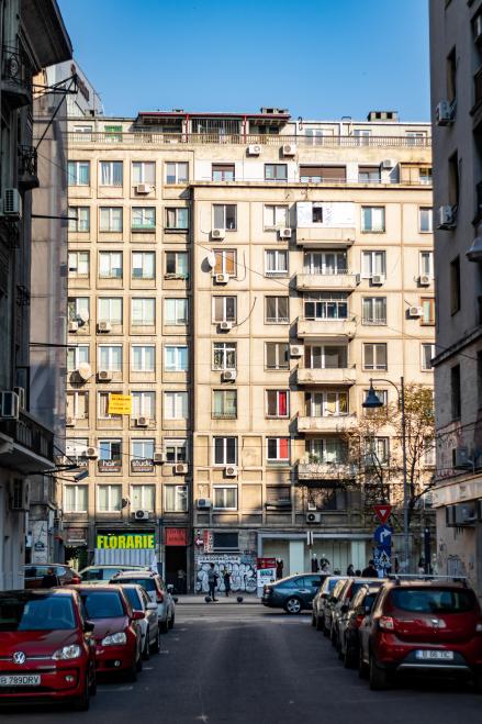 Blick aus einer Stra&szlig;e auf ein &auml;lteres mehrst&ouml;ckiges graues Geb&auml;ude  in Bucharest