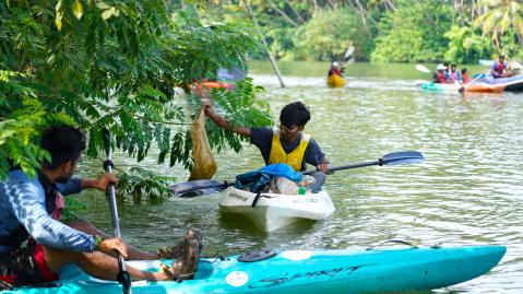 People in kayaks are taking out trash from the water