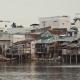 Tin huts stand on wooden pillars above a dirty body of water.