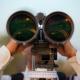 Person looks through large binoculars.