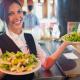 Pretty barmaid holding plates of salads in a bar