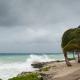 A hurricane is about to batter this caribbean beach hut. The seas are raging and the skies show the tropical storm as the power of nature is demonstrated. Waves crash on the shore